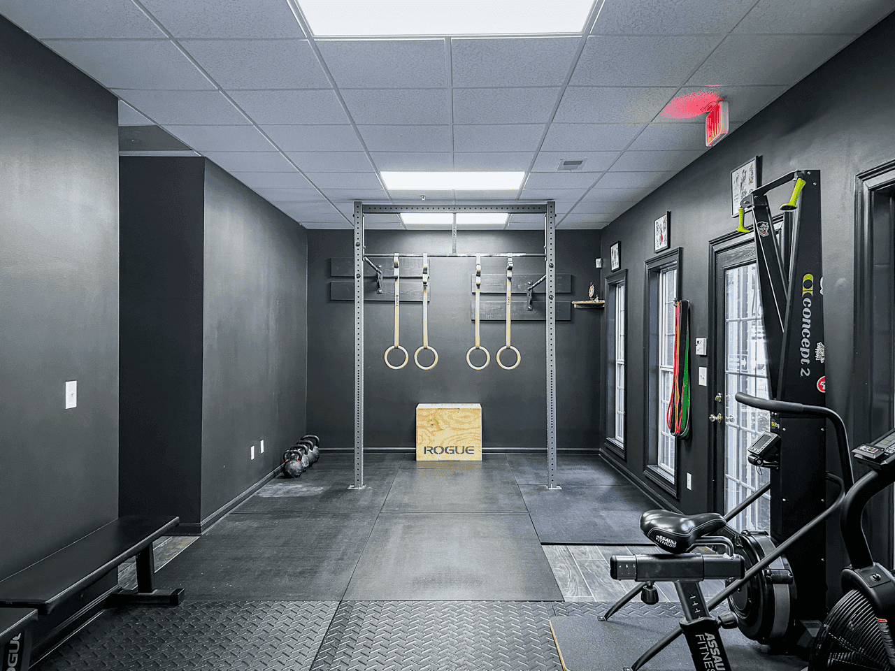 A squat rack with gymnastic rings, plyo box and kettlebells at Hustle House Health & Wellness in Woodstock, GA