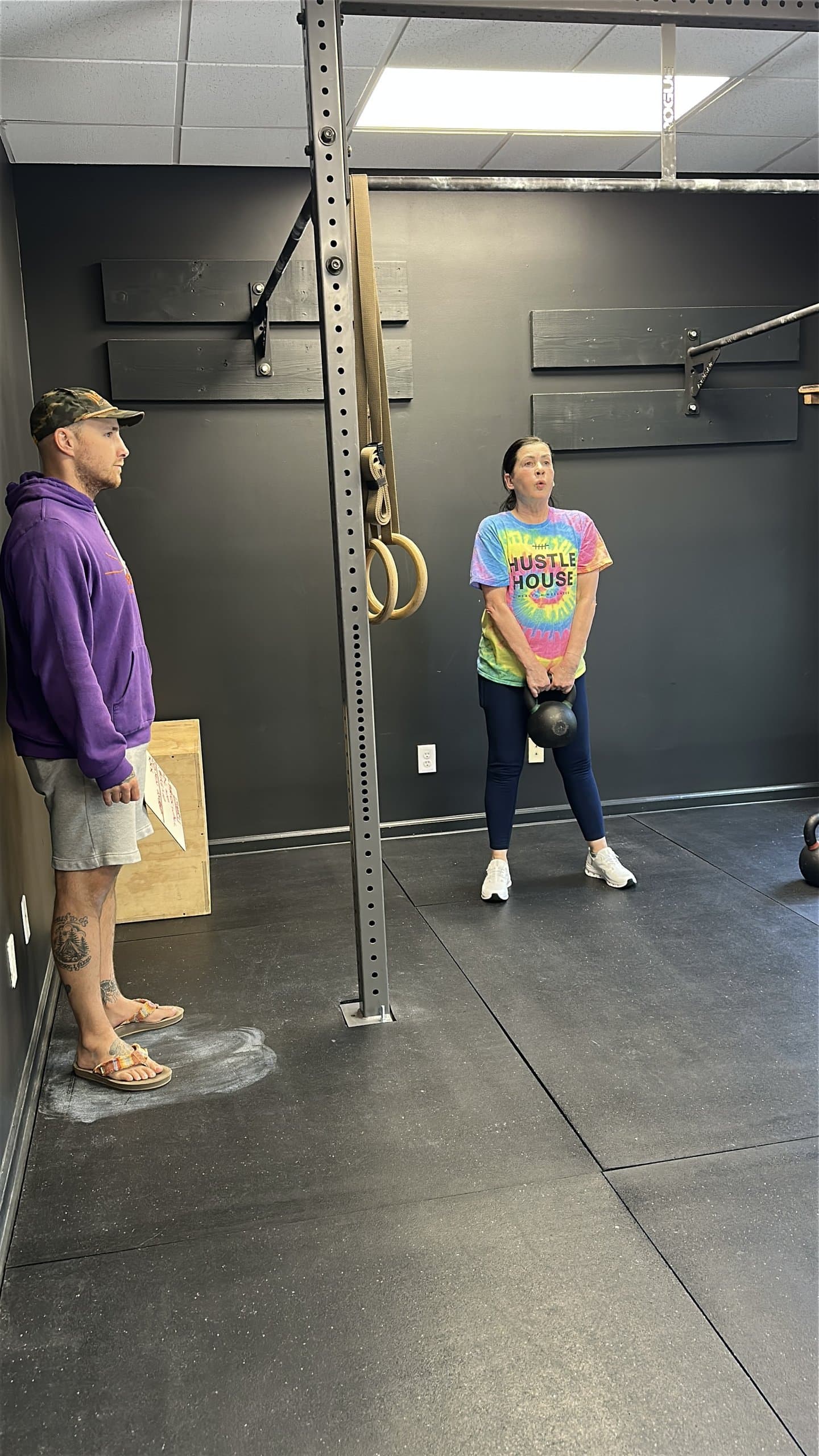 A coach guiding a member through a kettlebell exercise one-on-one at Hustle House Health & Wellness in Woodstock, GA