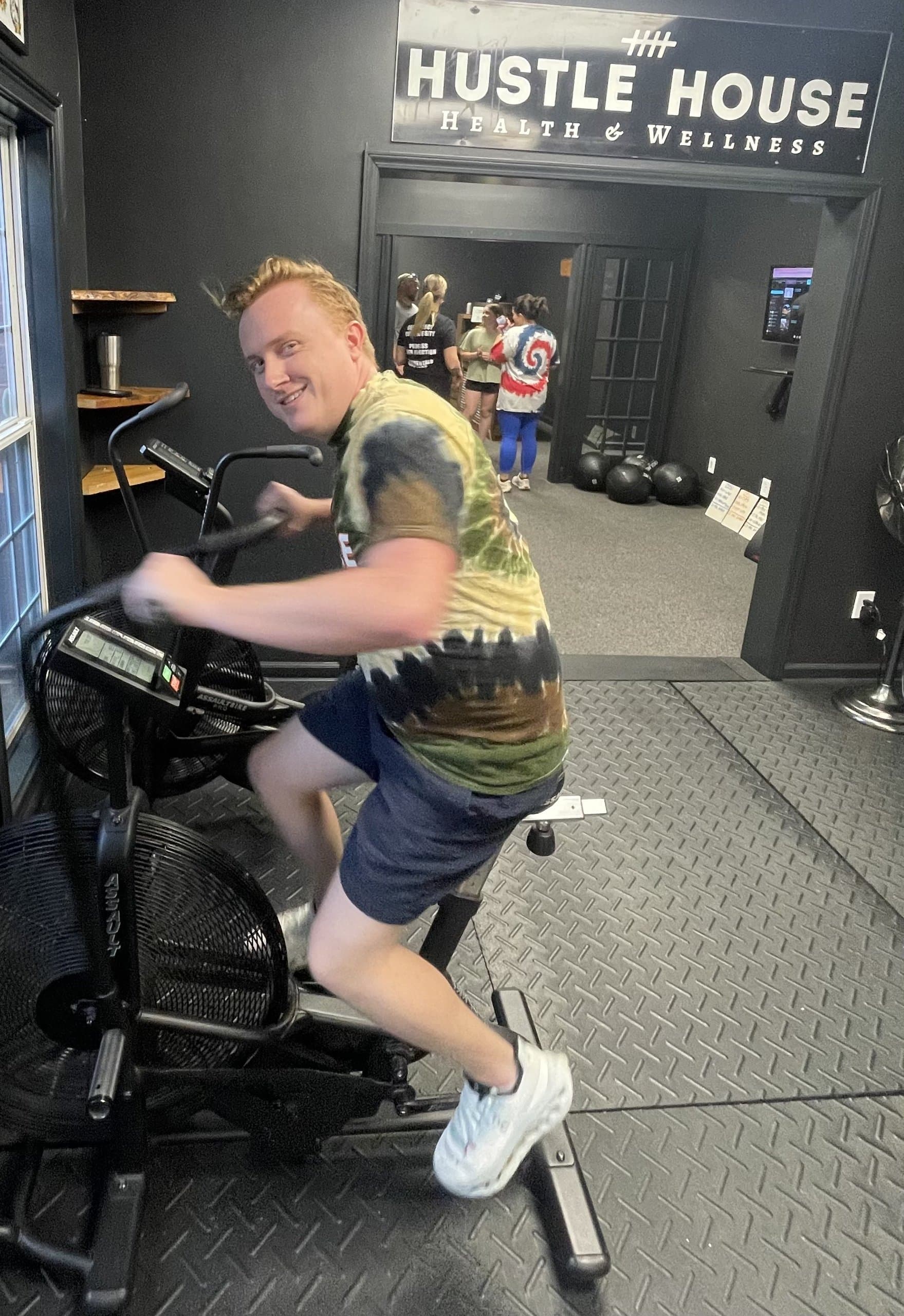 A member riding an air bike during class at Hustle House Health & Wellness in Woodstock, GA