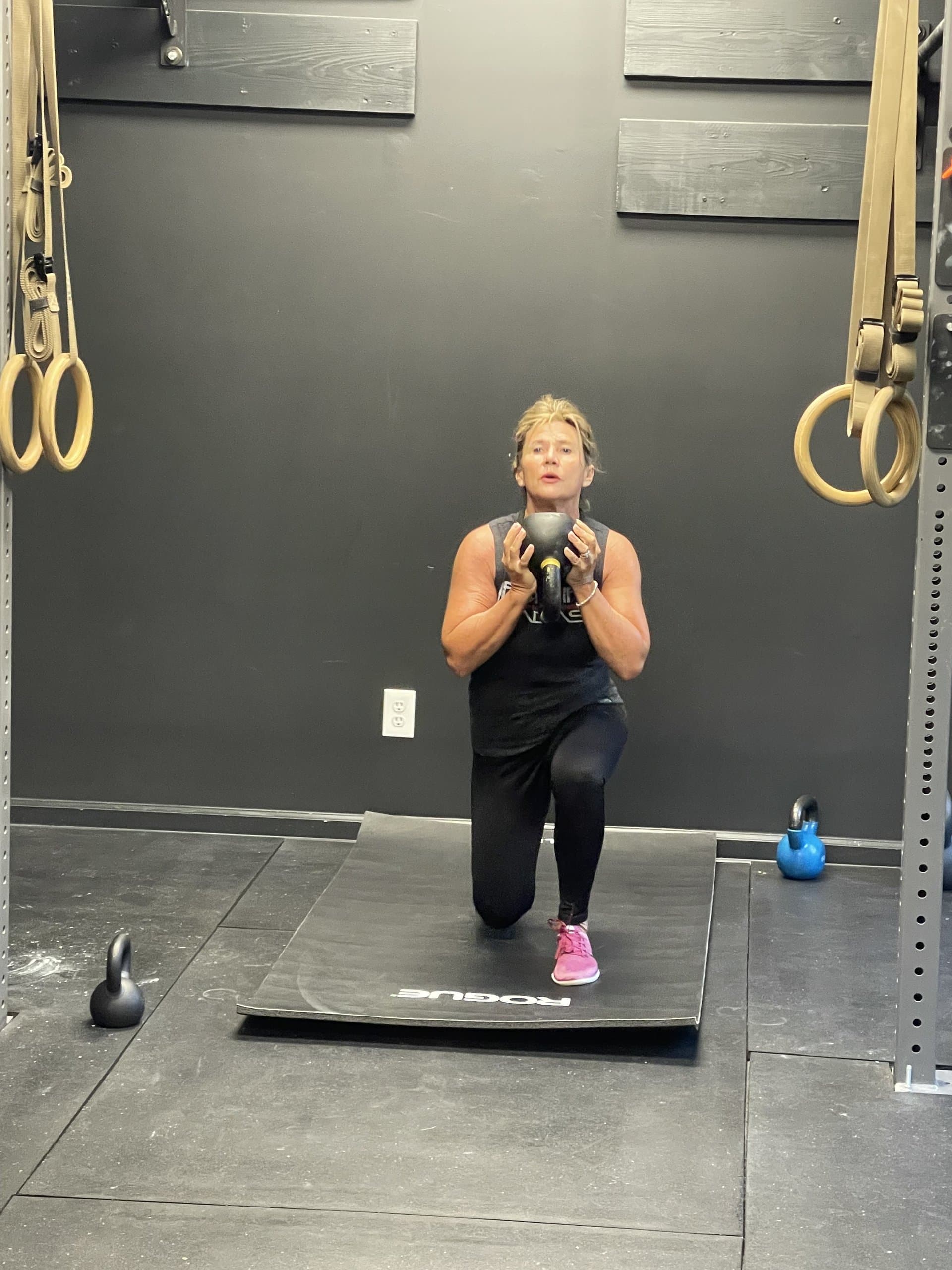 A member performing a kneeling kettlebell lunge with joint-friendly form at Hustle House Health & Wellness in Woodstock, GA